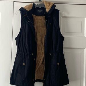 Black vest with brown fur . Hood